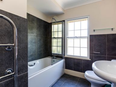 A bathroom with a bathtub shower combination a window a sink and a toilet at Lowenna Manor 10 Rock