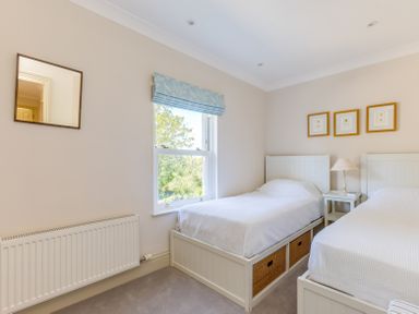 A bedroom with two single beds a window with blue blinds and framed pictures on the wall at Lowenna Manor 10 Rock
