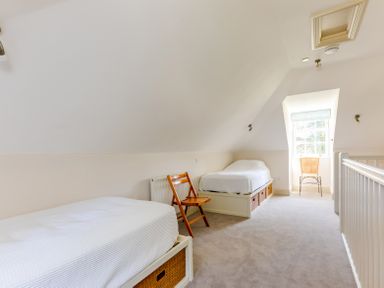 A bedroom with two single beds a wooden chair and a window at Lowenna Manor 10 in Rock