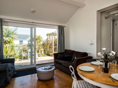 A living room with a sofa table and chairs and a sliding glass door leading to a patio at The Folly in Port Isaac