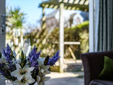 A bouquet of white and purple flowers inside near a door opening to a garden at The Folly in Port Isaac
