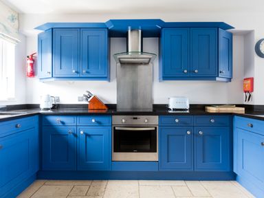 A kitchen with blue cabinets a stainless steel oven and hood a knife block toaster and kettle at Rock Lobster in Port Isaac