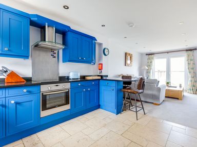A kitchen with blue cabinets and a living room with sofa and coffee table at Rock Lobster in Port Isaac