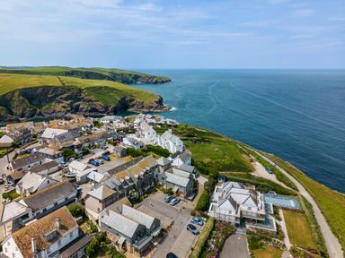 A coastal village with houses and a parking area near cliffs and the sea at Rock Lobster in Port Isaac