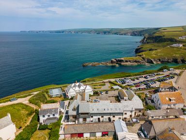 A coastal landscape with buildings near a parking lot and the sea at Rock Lobster in Port Isaac