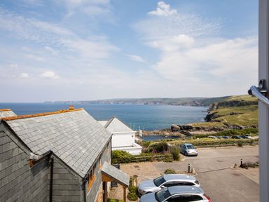 View of coastal houses parking lot sea and cliffs at Rock Lobster in Port Isaac