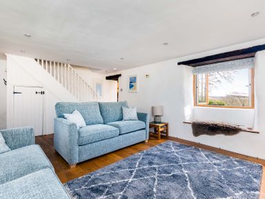 A living room with blue sofas a gray rug and a window seat at Dingles Cottage in Rock