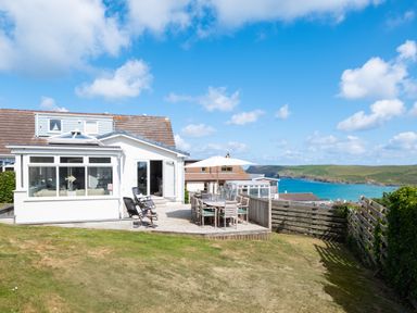 A house with a patio and outdoor dining furniture overlooking the sea at Atlantis in Polzeath