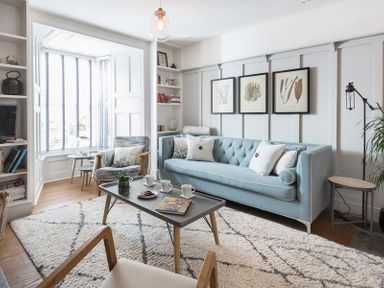 A living room with a light blue sofa three framed pictures on the wall and a coffee table with cups and a plant at Albany in Port Isaac