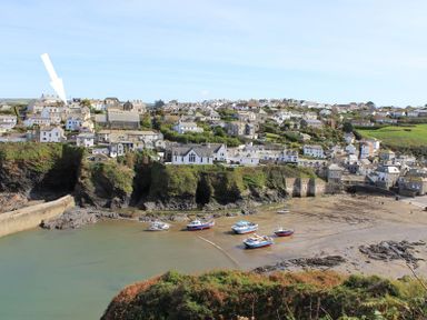 A coastal village with boats on the shore and houses on cliffs at Albany in Port Isaac