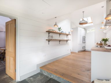 A kitchen with wooden floors white walls open wooden shelves and pendant lights at Albany in Port Isaac