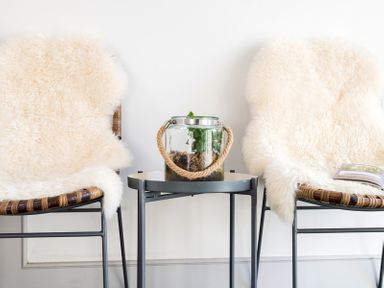 Two chairs with white fur covers and a small table with a glass terrarium between them at Albany in Port Isaac