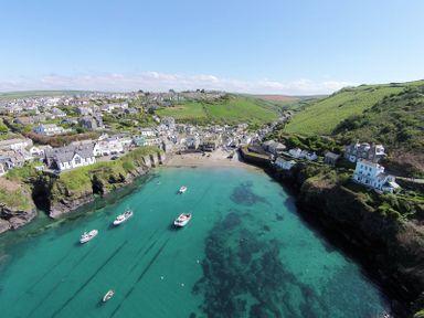 A coastal village with houses on hills and boats in clear water at Albany in Port Isaac
