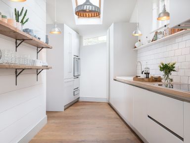 A kitchen with white cabinets wooden countertops open wooden shelves and hanging lights at Albany in Port Isaac
