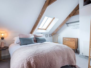A bedroom with a bed pillows and blanket skylight and wooden furniture at Albany Port Isaac