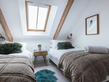 A bedroom with two single beds a skylight window and a small nightstand at Albany in Port Isaac