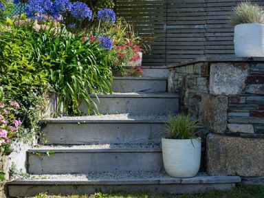 Outdoor wooden steps with gravel and potted plants next to a stone wall at Albany in Port Isaac