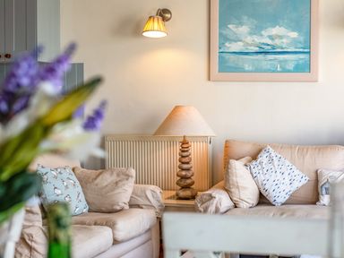 A seating area with beige sofas and patterned cushions a lamp on a side table and a painting on the wall at Slipway 12 in Rock