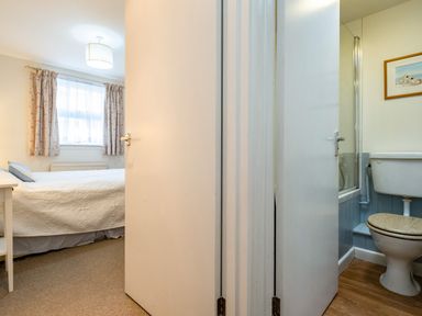 A bedroom with a bed and window next to a bathroom with a toilet and framed picture at Slipway 12 in Rock