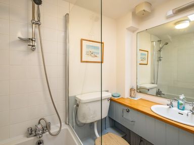 A bathroom with a bathtub shower combo toilet and a sink with wooden countertop at Slipway 12 in Rock