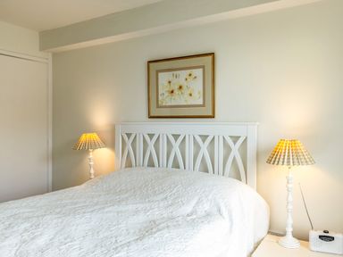 A bedroom with a white bed headboard two bedside lamps and a painting above the bed at Slipway 12 in Rock