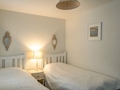 A bedroom with two single beds a bedside table and lamp two decorative mirrors and a framed picture at Slipway 12 in Rock