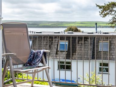 A chair with a cloth draped over it on a balcony with a view of rooftops and countryside at Slipway 12 in Rock