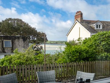 A view of a garden with green bushes and wooden fence overlooking houses trees and water with boats at Slipway 12 in Rock
