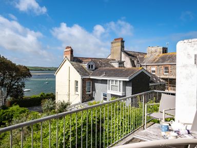 A balcony with chairs and a table overlooking houses and a body of water at Slipway 12 in Rock