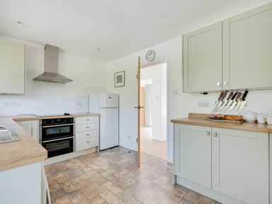 A kitchen with an oven fridge knives and kitchen cabinets at Tremay in Rock