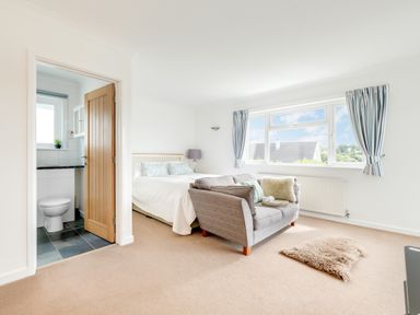 A bedroom with a bed a sofa a window with curtains and an en suite bathroom at Tremay in Rock