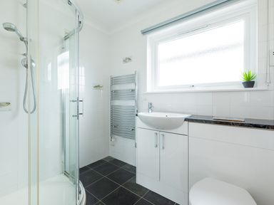 A bathroom with a shower enclosure sink toilet towel rack and a window with a plant on the sill at Tremay in Rock