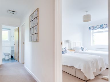 A hallway leading to a bathroom and a bedroom with two single beds at Tremay in Rock