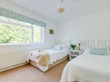 A bedroom with two single beds a nightstand with a lamp and plant next to a large window at Tremay in Rock