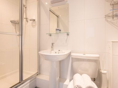 A bathroom with a shower cubicle sink toilet and towels at Lundy Cottage in Rock