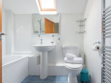 A bathroom with a bathtub sink toilet mirror towel rack and skylight at Lundy Cottage in Rock