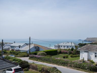 A coastal residential area with houses gardens and a view of the sea at The Point in Polzeath