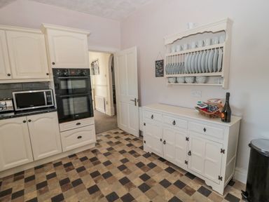 A kitchen with cream cabinets double oven microwave dish rack and sideboard with dishes at Cheviot Hills in Wooler