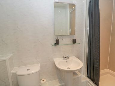 A bathroom with a toilet sink mirror and shower with a dark curtain at Cheviot Hills in Wooler