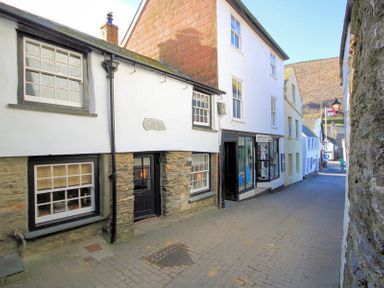 A narrow paved street with old buildings and shopfronts in a small town at Cloam Cottage in Port Isaac