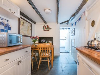 A kitchen with wooden countertops a dining table with chairs and a microwave at Cloam Cottage Port Isaac