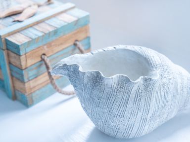 A decorative white shell and a striped wooden box with rope handles at Cloam Cottage in Port Isaac