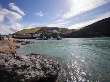 A coastal scene with boats on water near rocky shore and houses on hills at Cloam Cottage in Port Isaac