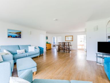 A living room with blue sofas and armchairs wooden dining table and chairs a flat screen television and wooden floor at Rock Hill in Rock