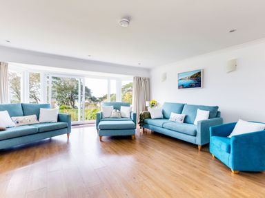 A living room with three blue sofas a large window and wooden flooring at Rock Hill in Rock