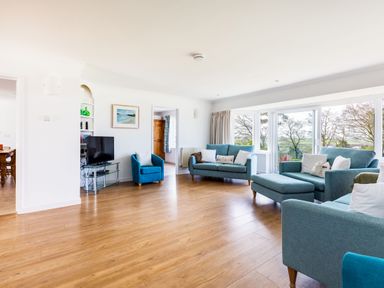 A living room with blue sofas a television on a glass stand hardwood floor and large windows at Rock Hill in Rock