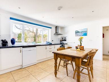 A kitchen with white cabinets a wooden dining table with chairs and a window with a blue blind at Rock Hill in Rock