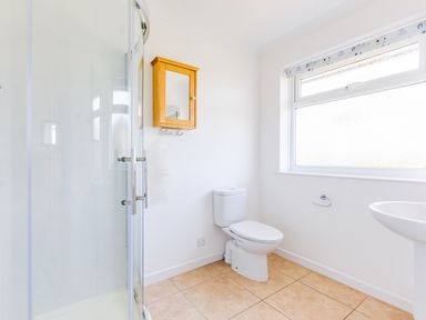 A bathroom with a shower enclosure toilet wooden wall cabinet and a window at Rock Hill in Rock