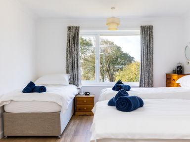 A bedroom with two single beds rolled towels on beds curtains on window and wooden furniture at Rock Hill in Rock