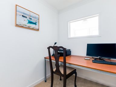 A small home office with a wooden desk and dark wooden chair a computer monitor keyboard printer and a painting of boats on the wall at Rock Hill in Rock